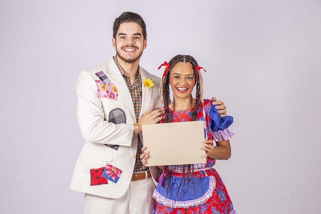 Casal de quadrilheiros trajados para festa junina segurando plaquinha