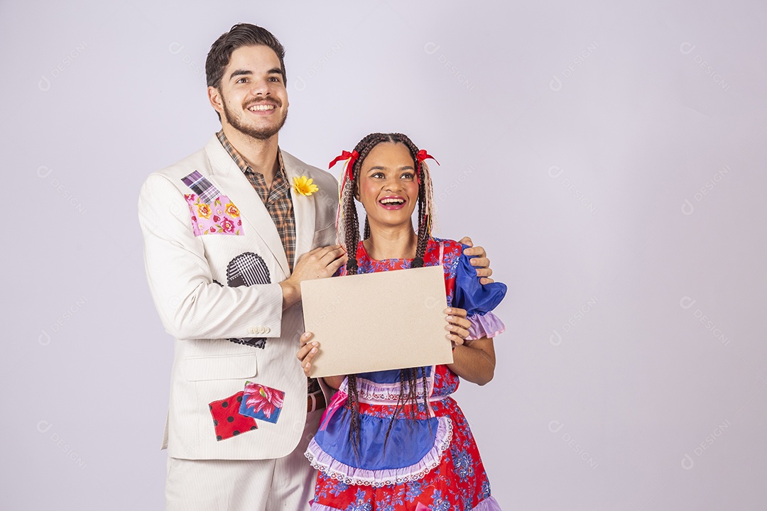 Casal de quadrilheiros trajados para festa junina segurando plaquinha