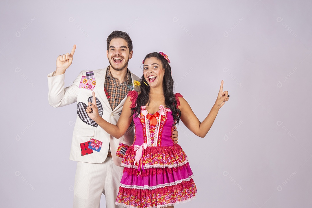 Casal a caráter para festa de são joão sorrindo com mãos para cima