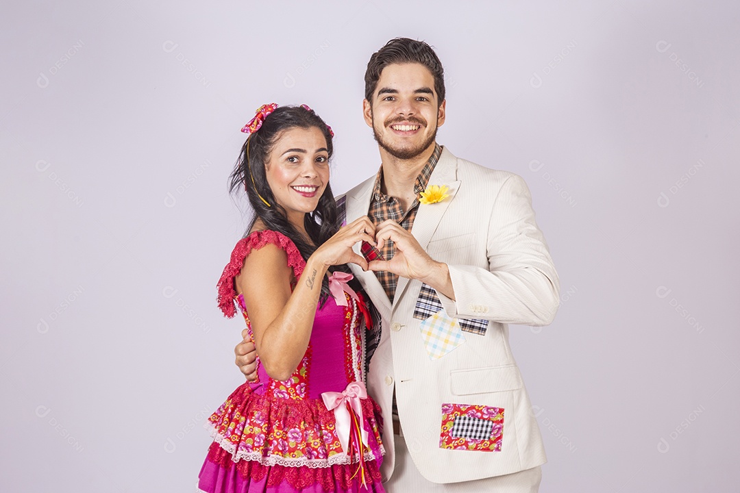 Casal a caráter para festa de São João abraçados fazendo coração