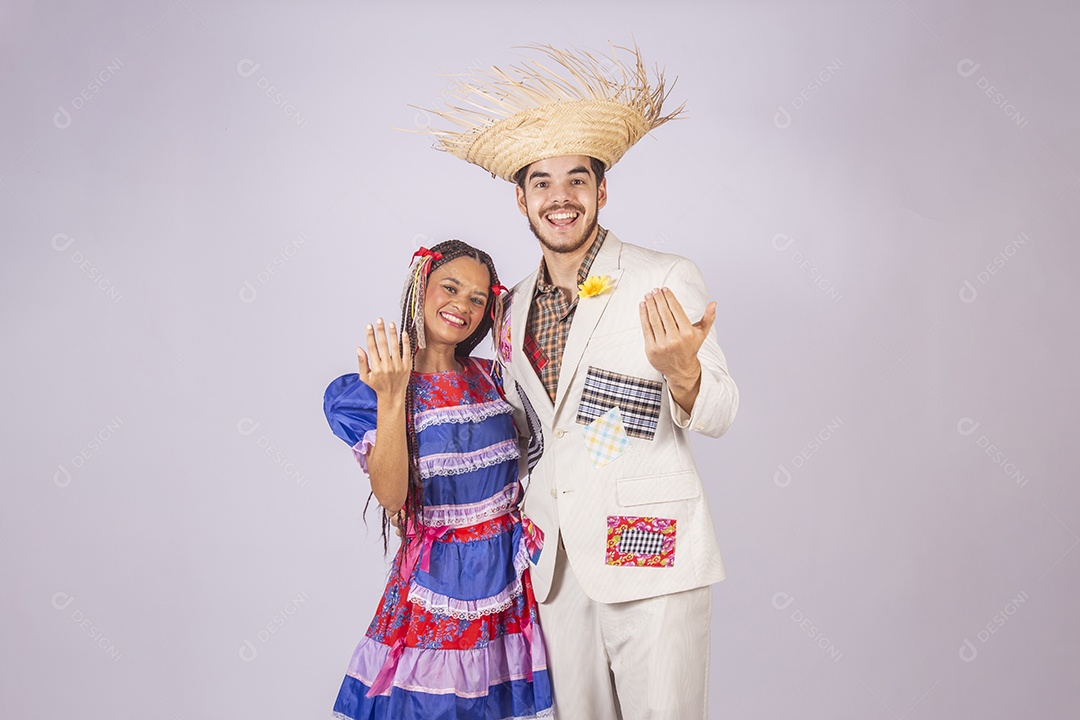 Casal de quadrilheiros juninos com gesto de chamar e sorrindo