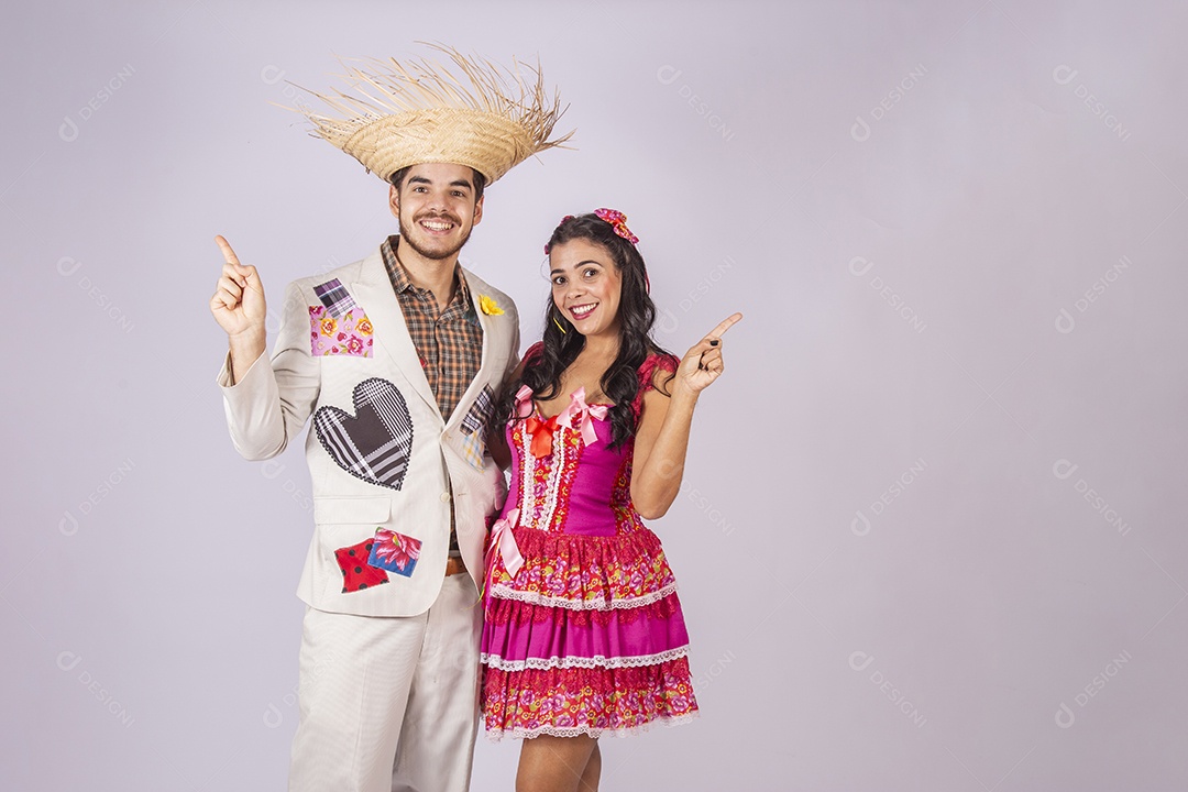 Casal de quadrilheiros trajados para festa junina apontando para os lados