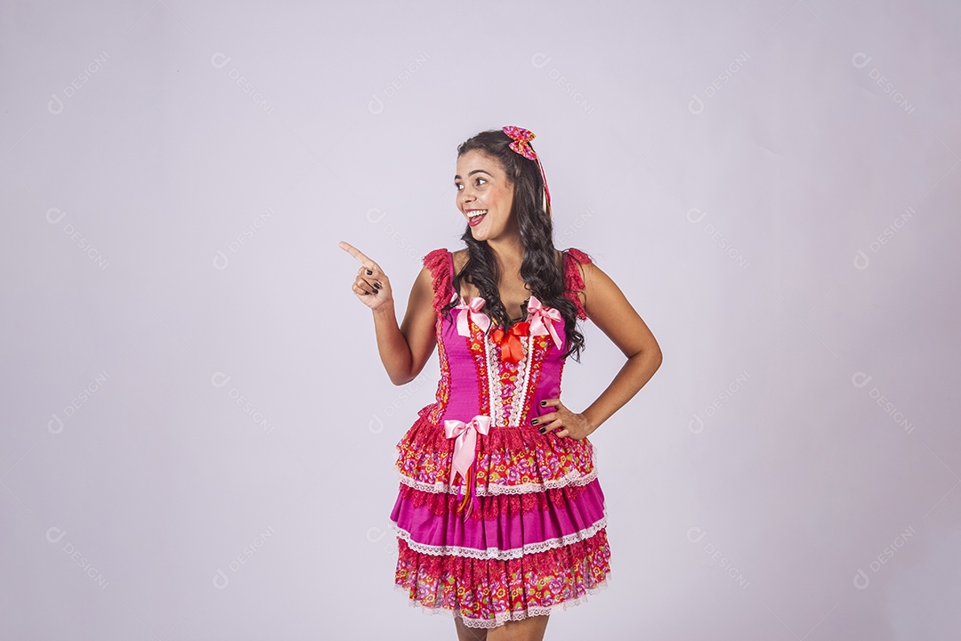 Mulher trajada para quadrilha sorrindo apontando para o lado