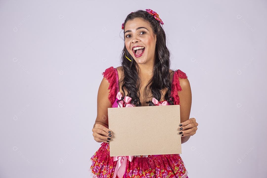 Mulher trajada para quadrilha junina sorrindo segurando plaquinha
