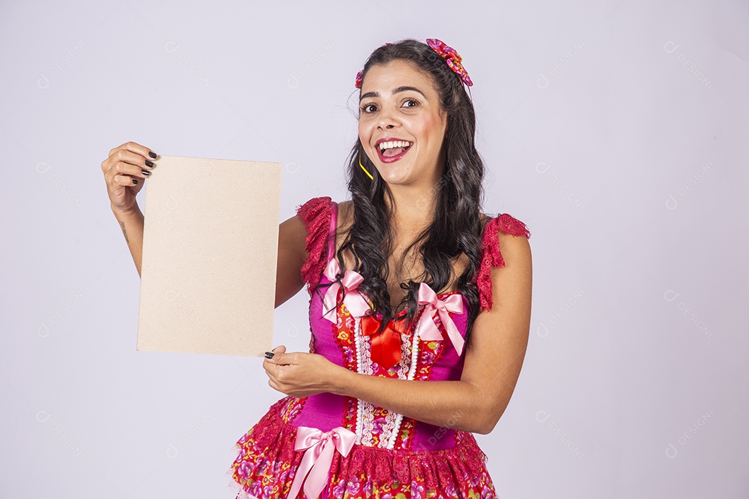 Mulher trajada para quadrilha junina sorrindo segurando plaquinha