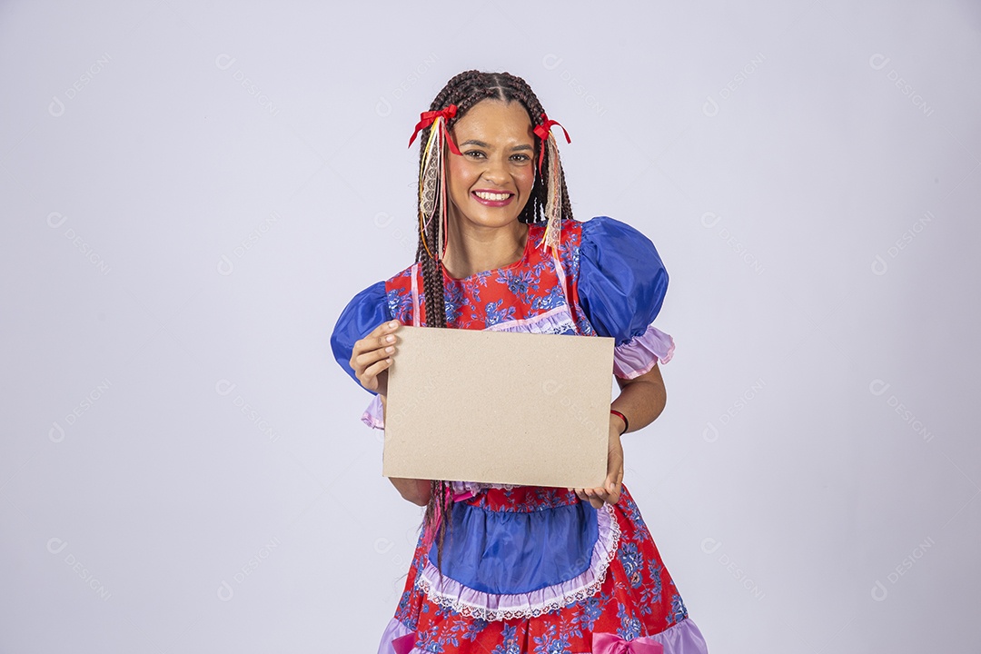 Mulher trajada para quadrilha junina sorrindo com plaquinha na mão