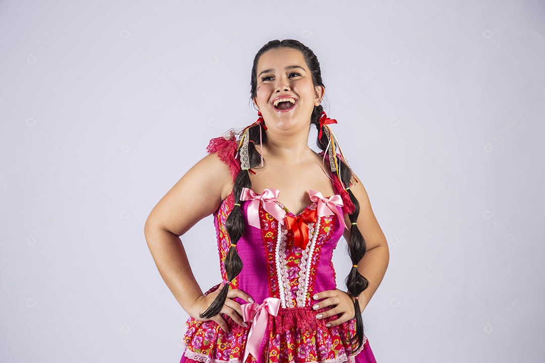 Mulher vestida de trajes junino com mãos na cintura e sorrindo