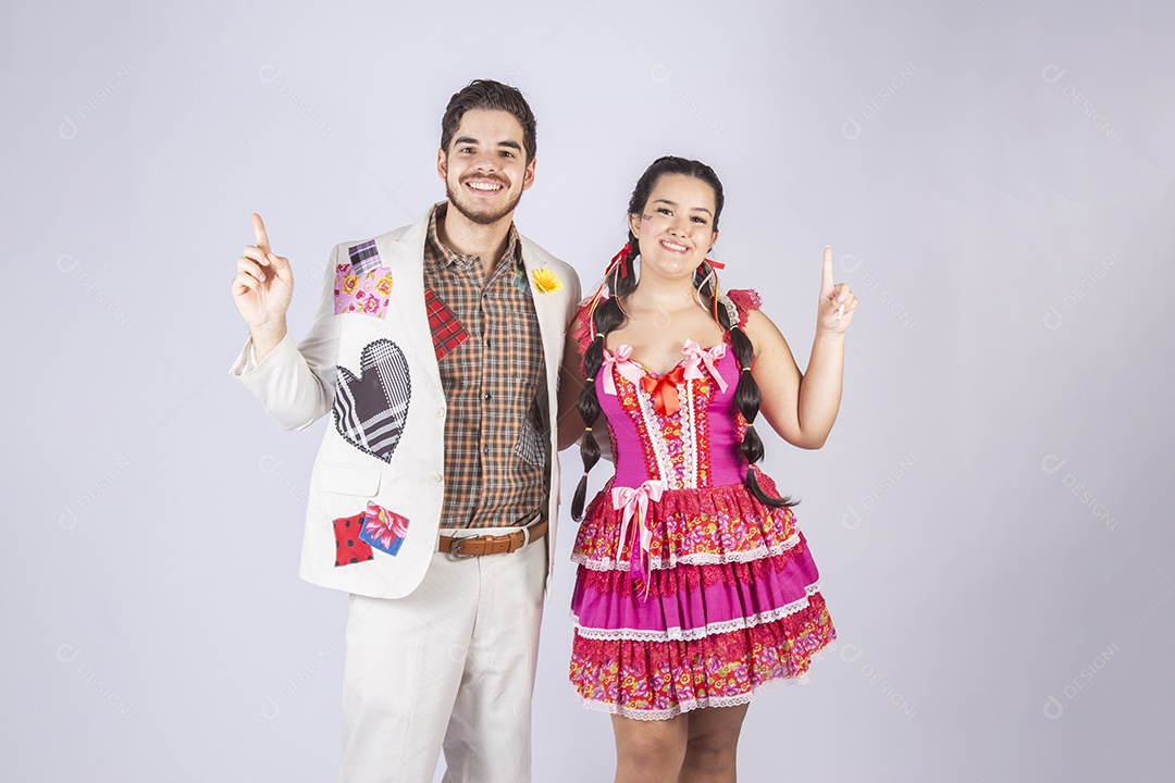 Casal a caráter para festa de São João abraçados apontando para cima