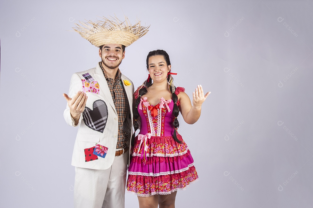 Casal a caráter para festa de São João abraçados com gesto de chamar