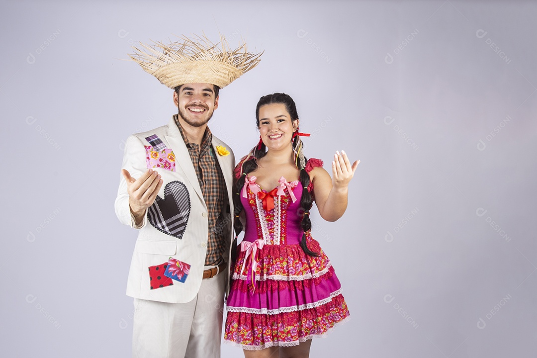 Casal a caráter para festa de São João abraçados com gesto de chamar