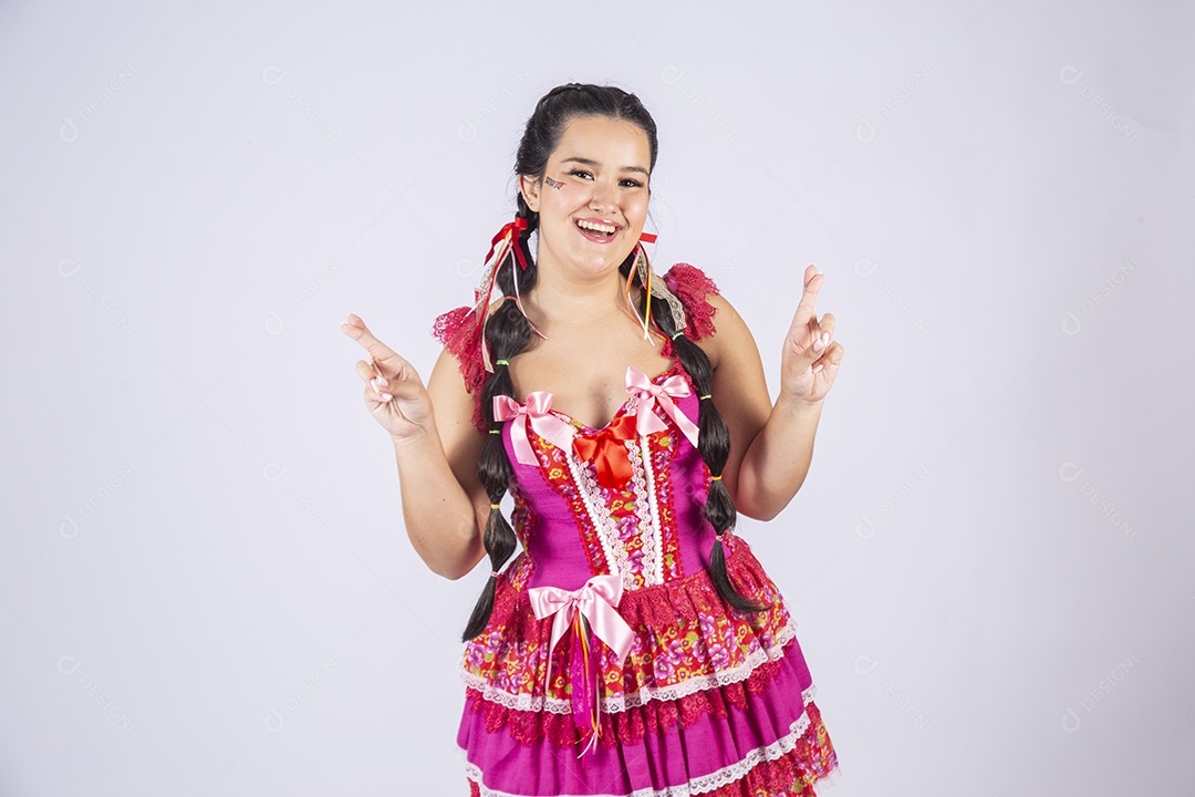 Menina com trajes e penteado para festa junina e dedos cruzados