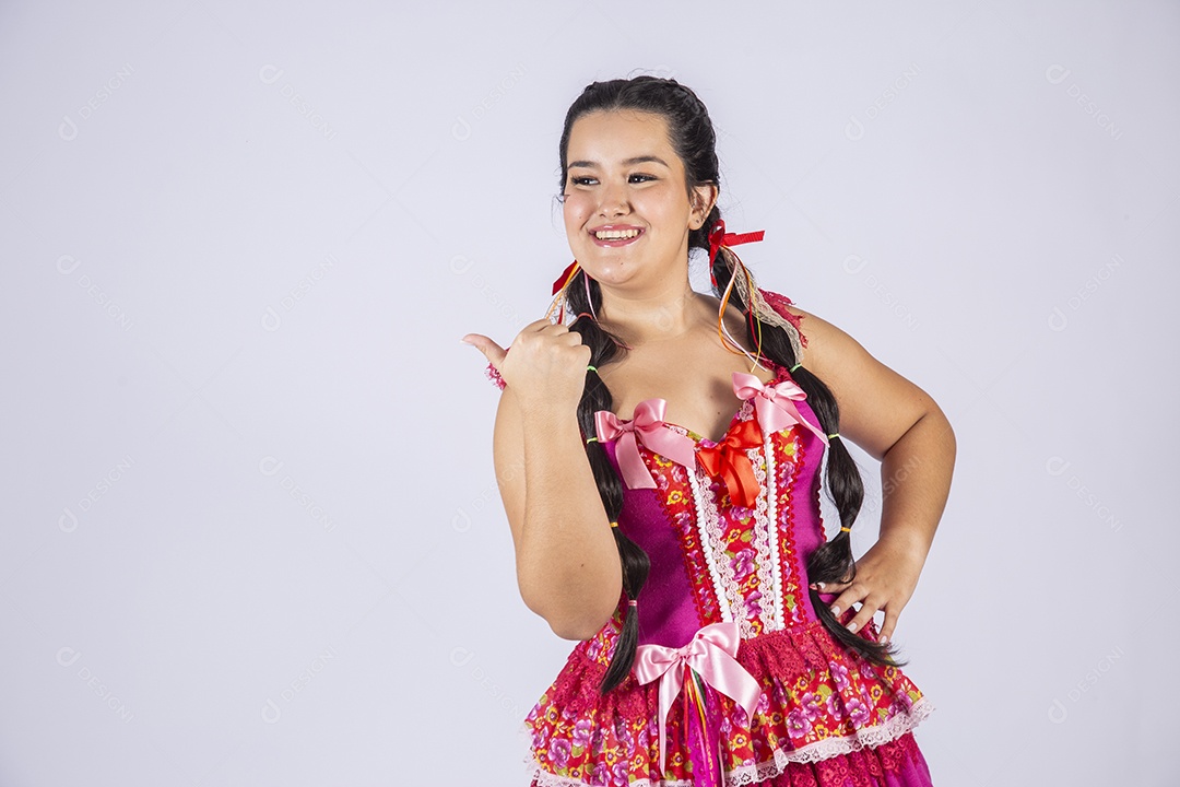 Menina com trajes e penteado para festa junina apontando para o lado