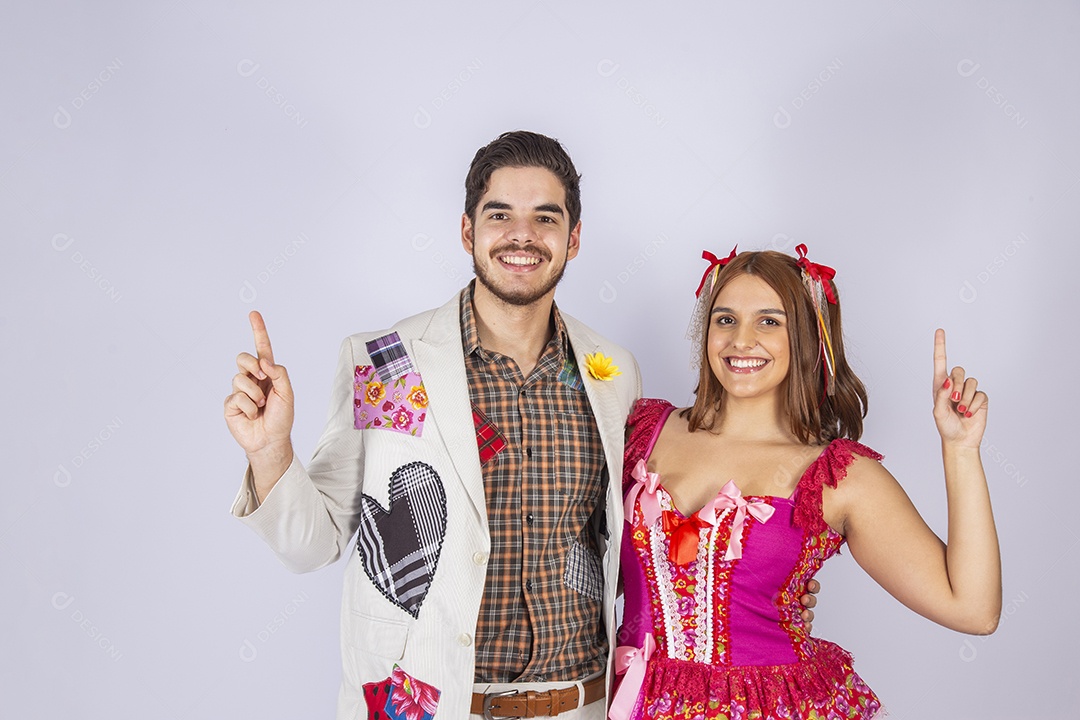 Casal de quadrilheiros trajados para festa junina apontando para cima