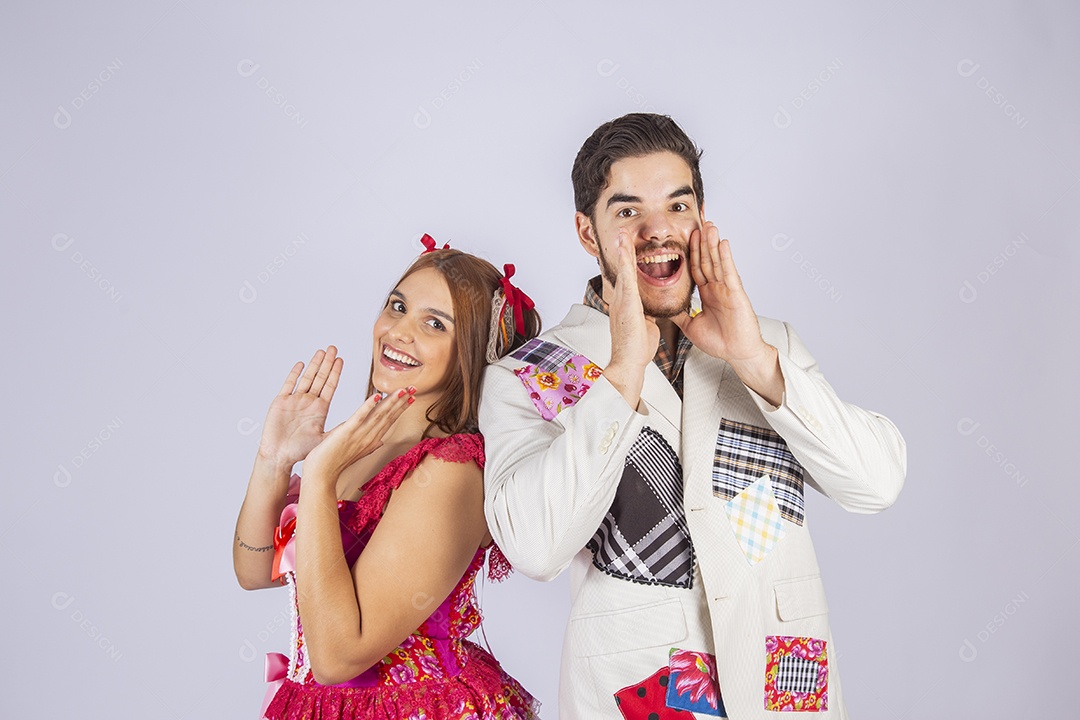 Casal de jovem quadrilheiros trajados para festa junina gritando