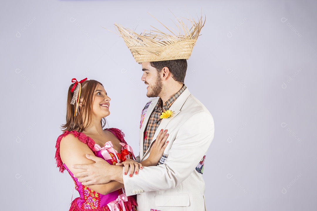 Casal de quadrilheiros juninos de braços dados e sorrindo
