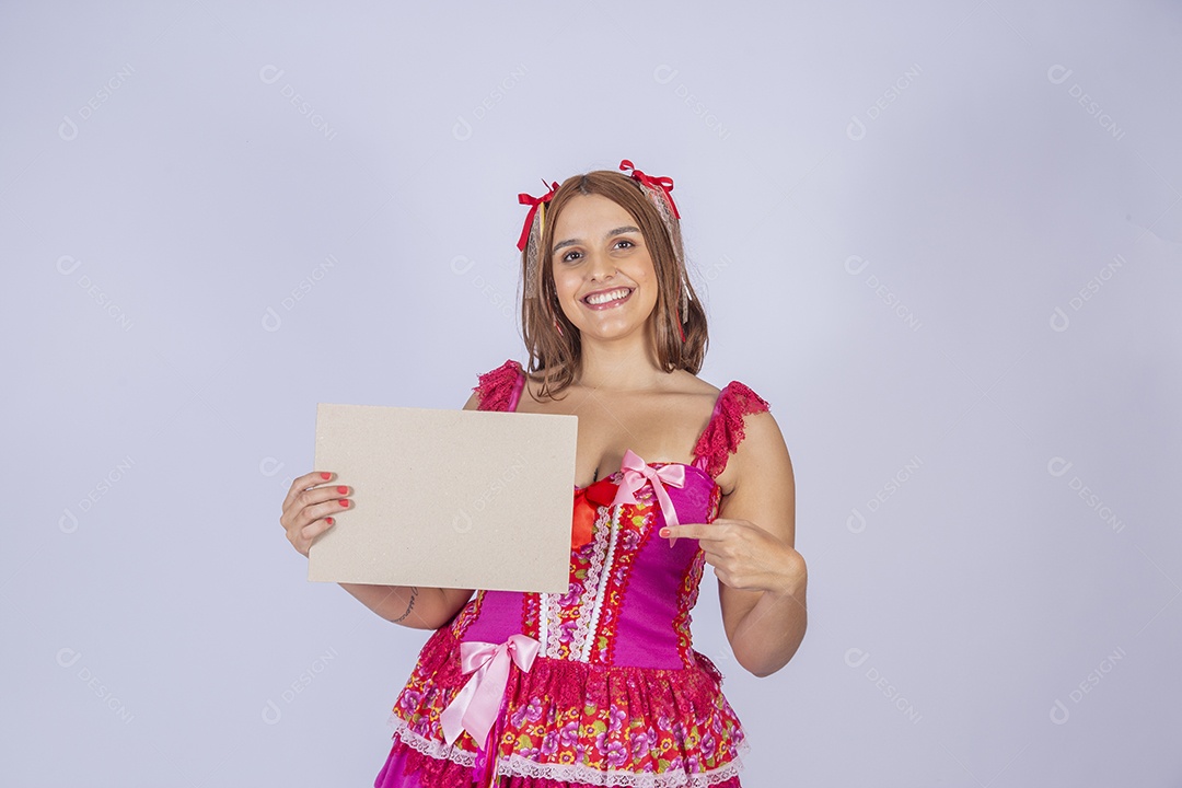 Jovem quadrilheira sorrindo e com trajes para festa junina com plaquinha