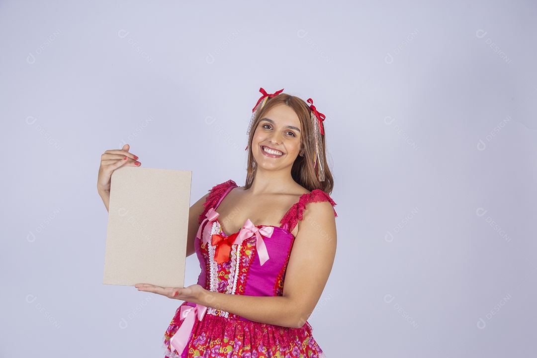 Jovem quadrilheira sorrindo e com trajes para festa junina com plaquinha