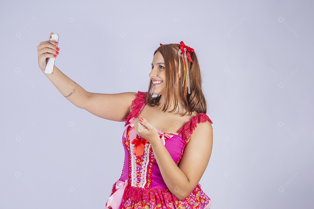 Jovem quadrilheira sorrindo e com trajes para festa junina tirando self