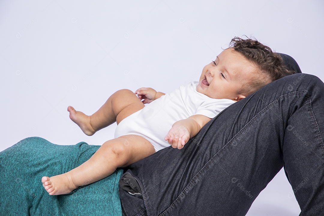 Um bebê fofinho sorrindo na perna de uma pessoa