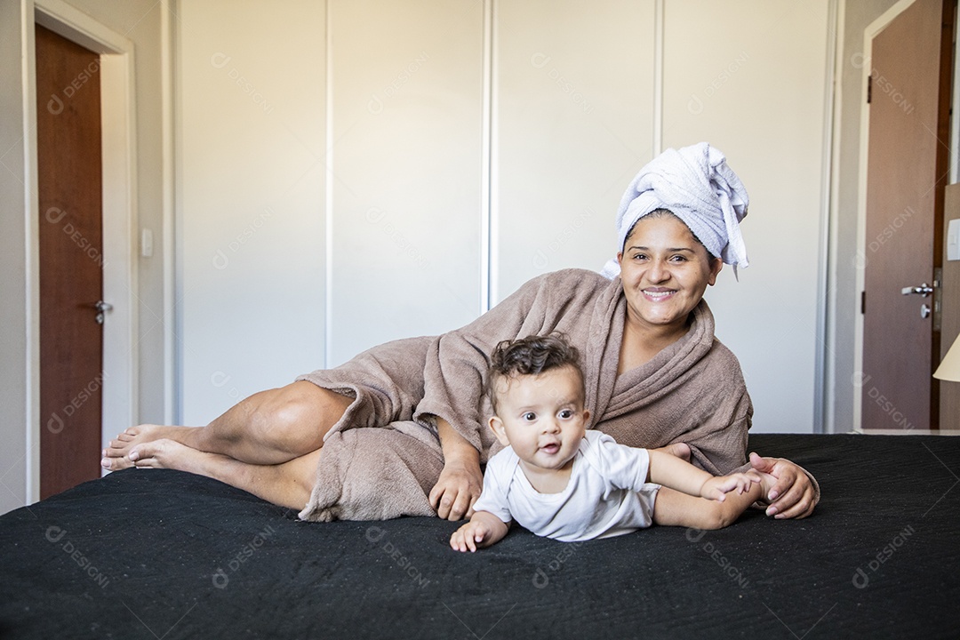 Mãe com seu bebê deitados na cama felizes