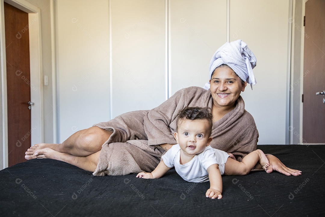 Uma mãe muito feliz brincando com seu bebê na cama