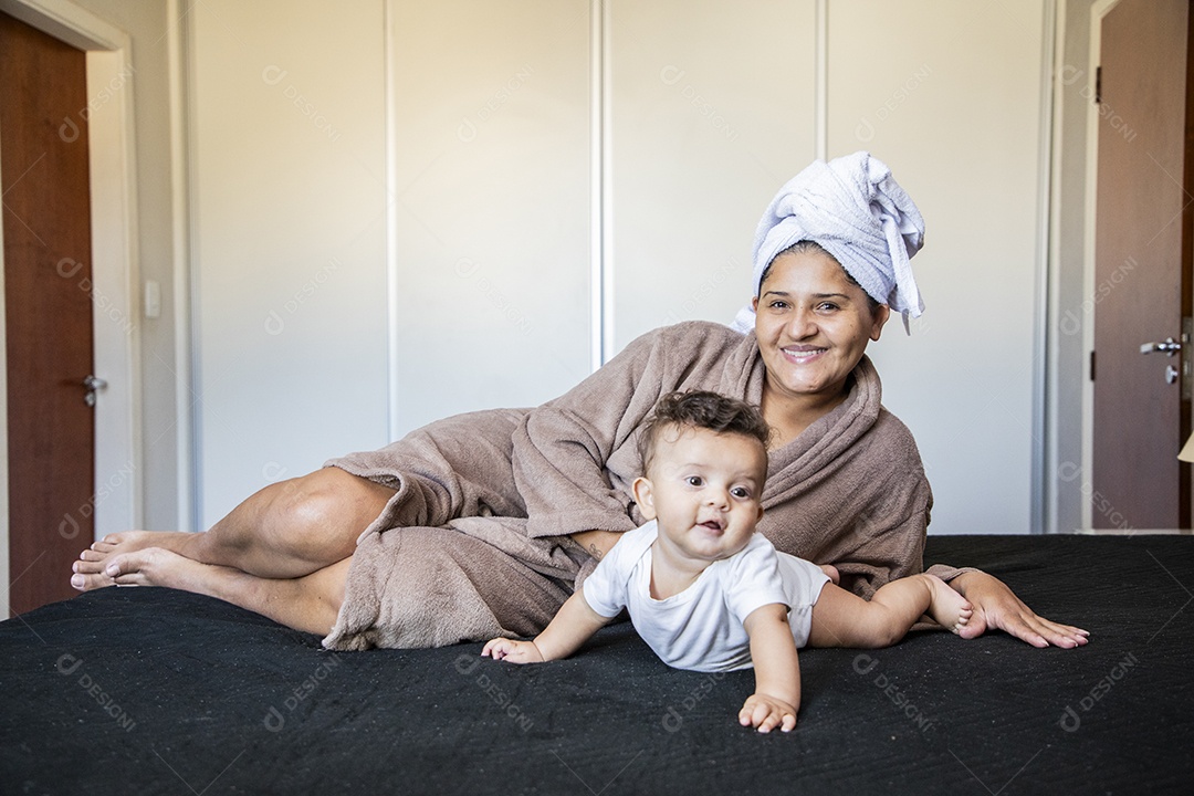 Uma mãe muito feliz brincando com seu bebê na cama