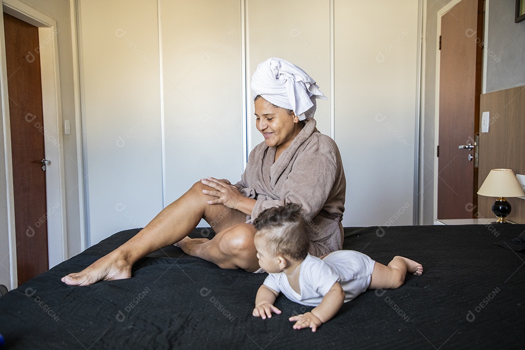Uma mãe muito feliz brincando com seu bebê na cama