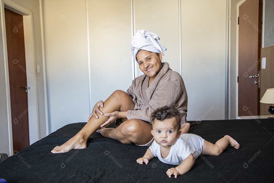 Mãe e filhos sentados na cama se divertindo