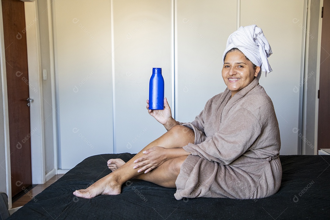 Mulher usando roupão de banho e passando creme hidratante