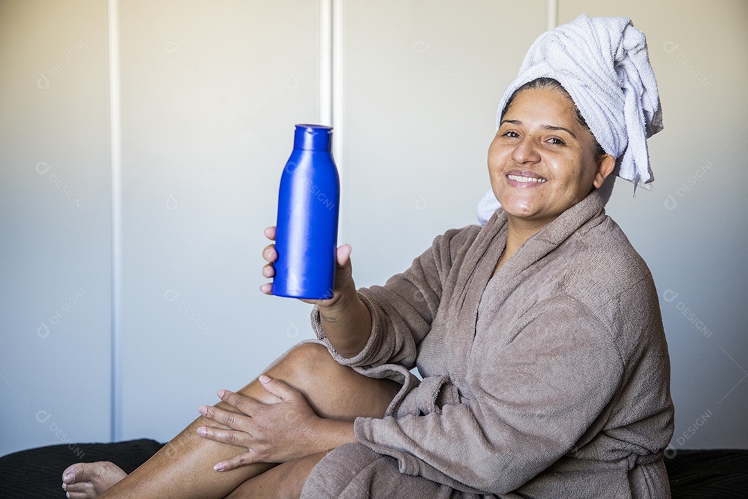 Mulher feliz usando roupão e usando creme de pele