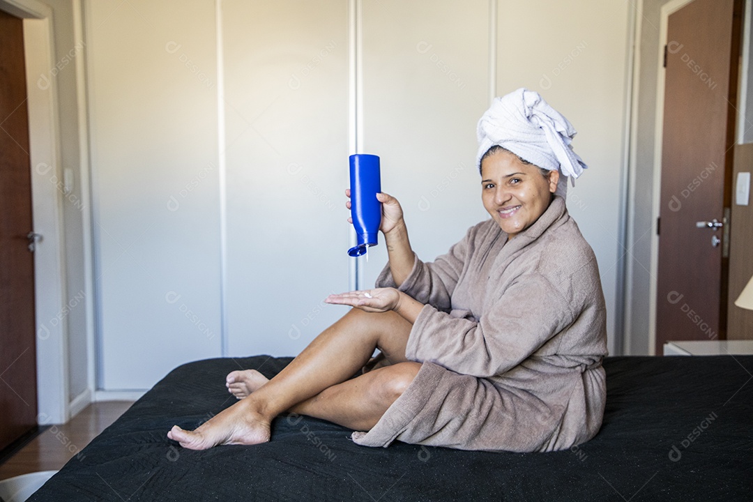 Mulher usando roupão feliz e passando hidratante