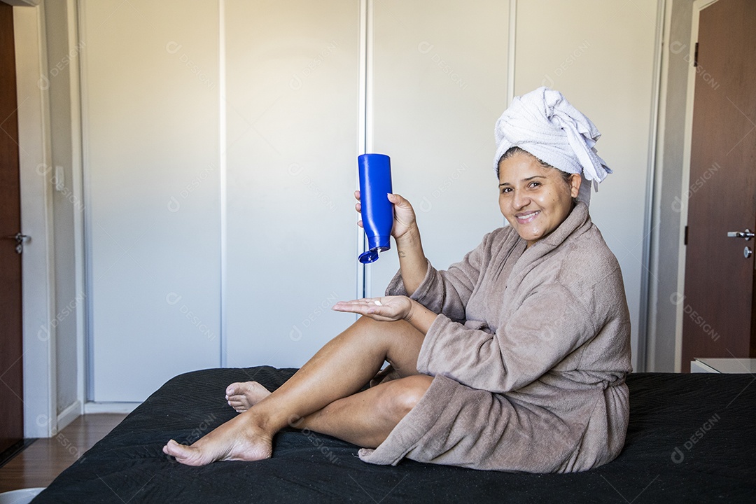 Mulher com roupão e passando hidrante