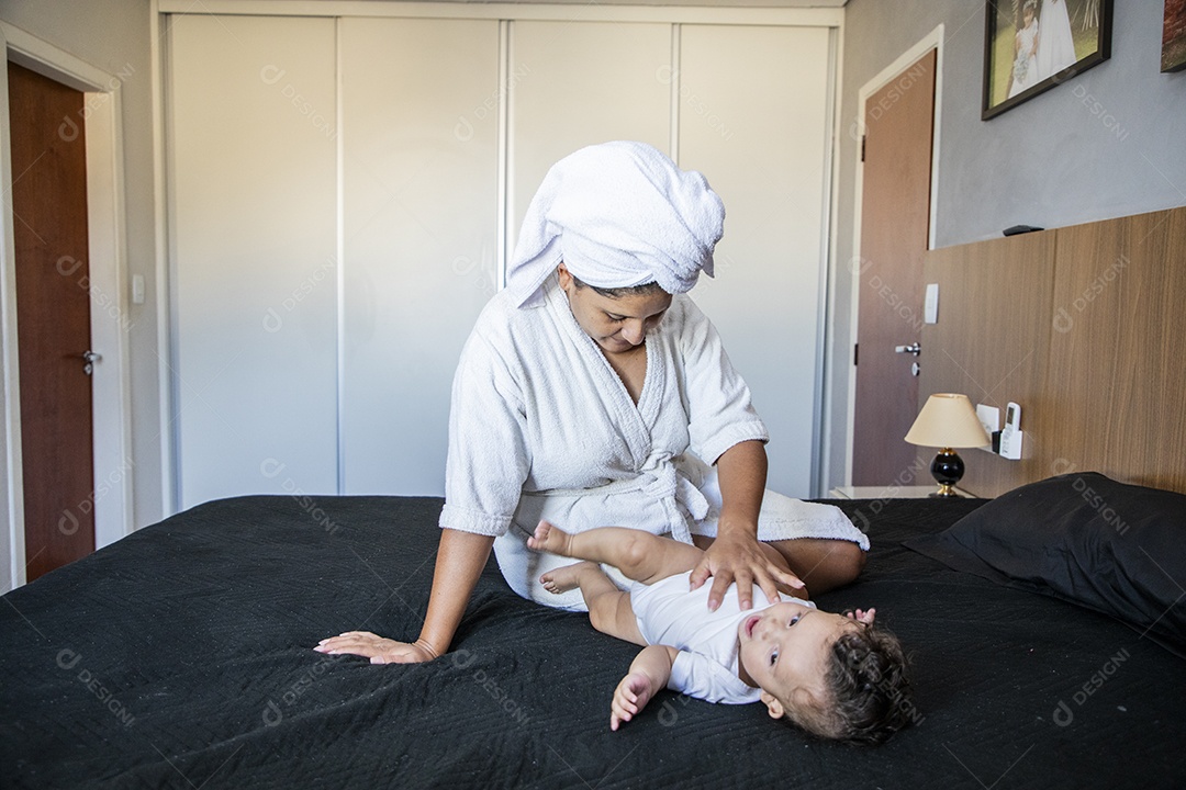 Mãe alegre e brincando com seu bebê na cama