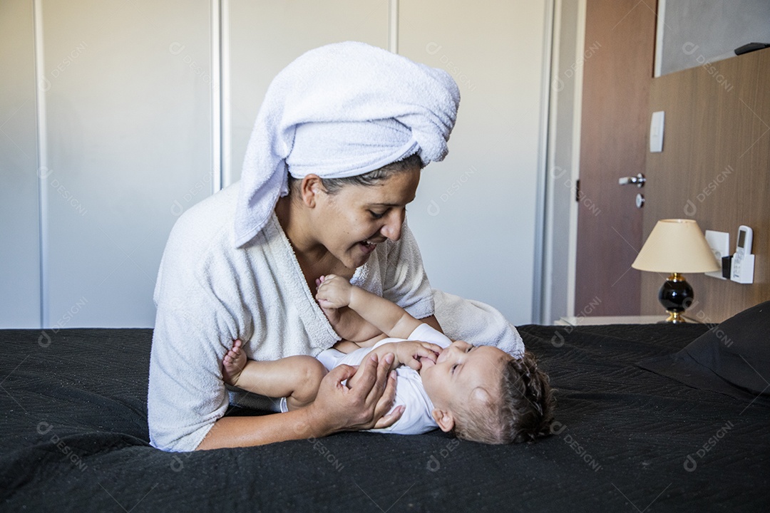 Mãe brincando com seu bebê na cama