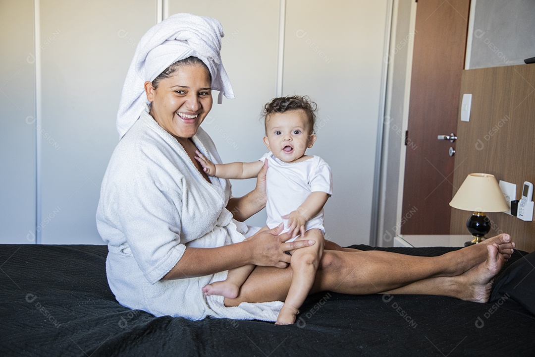 Mãe contente olhando e segurando seu bebê no colo