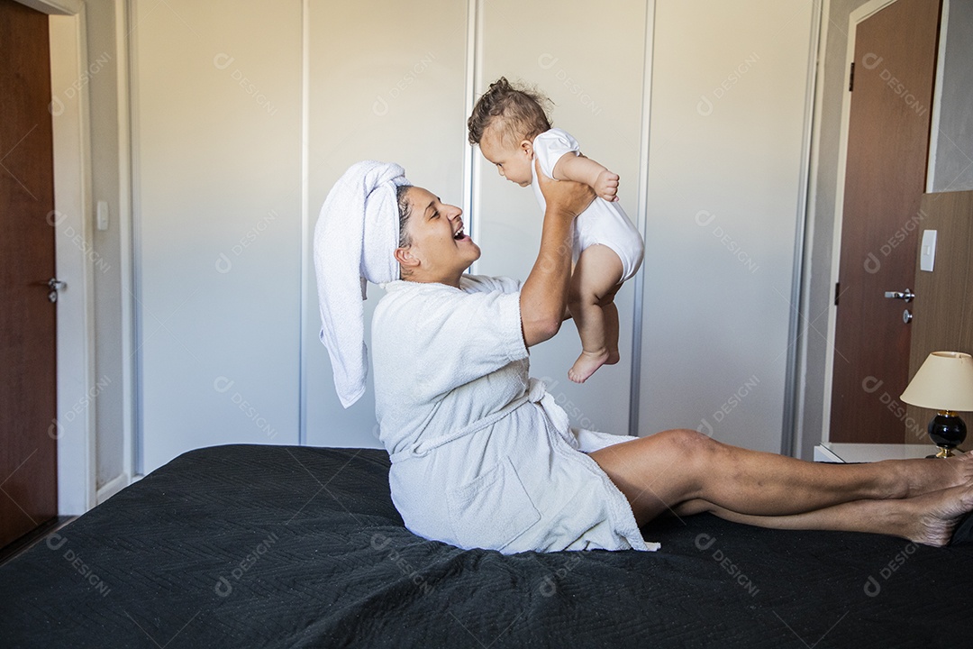 Uma mãe muito feliz com seu bebê na cama