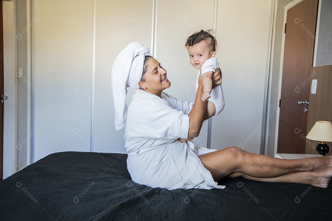 Uma mãe muito feliz brincando com seu bebê na cama