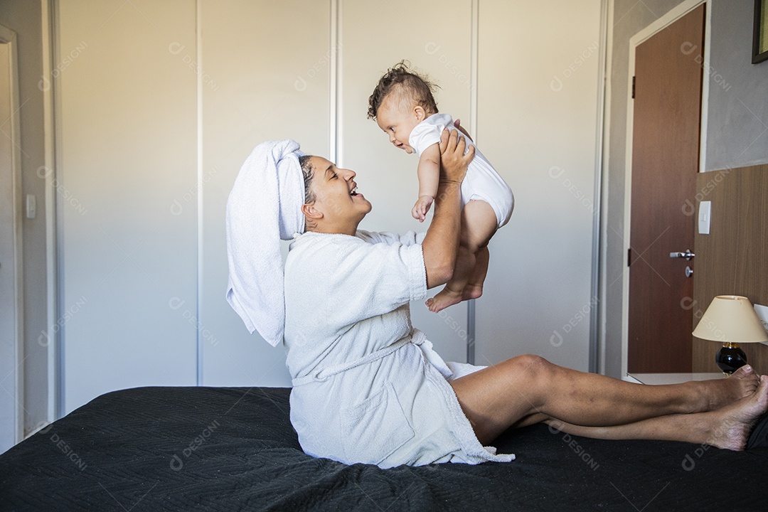 Mãe brincando com seu bebê na cama