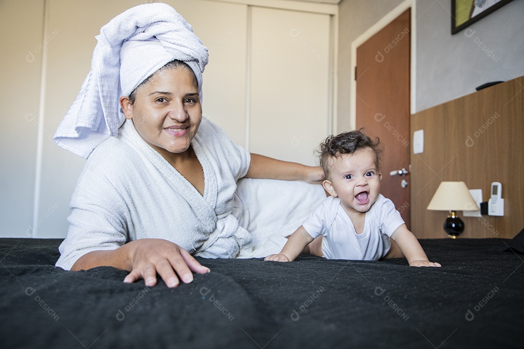 Mãe feliz com seu bebê deitados na cama depois de um banho