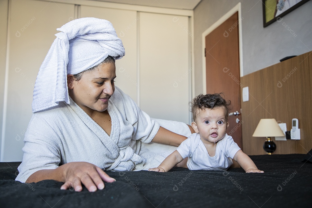 Mãe e seu bebê após banho deitados na cama