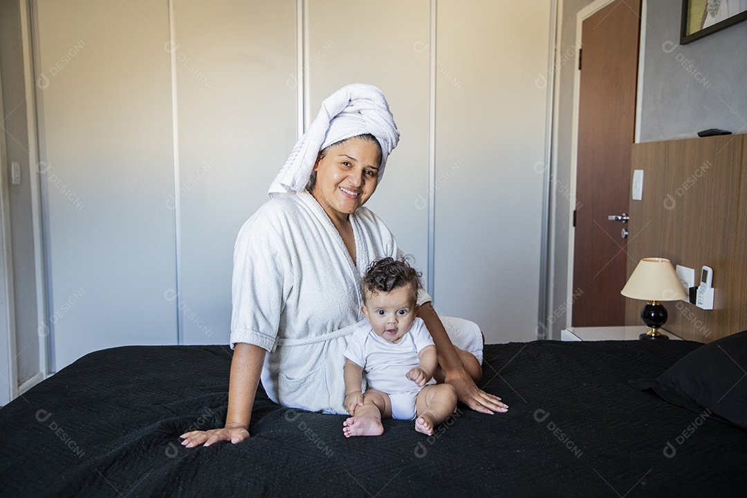 Mãe e seu bebê após banho sentados na cama