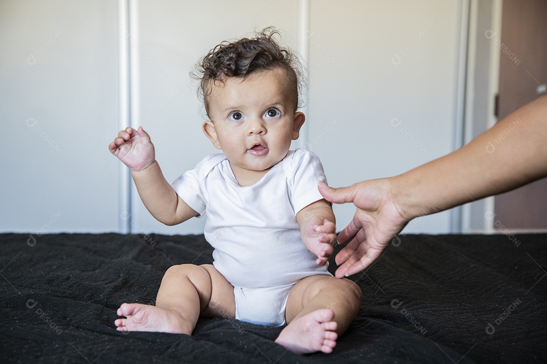 Um bebê lindo sentando na cama brincando