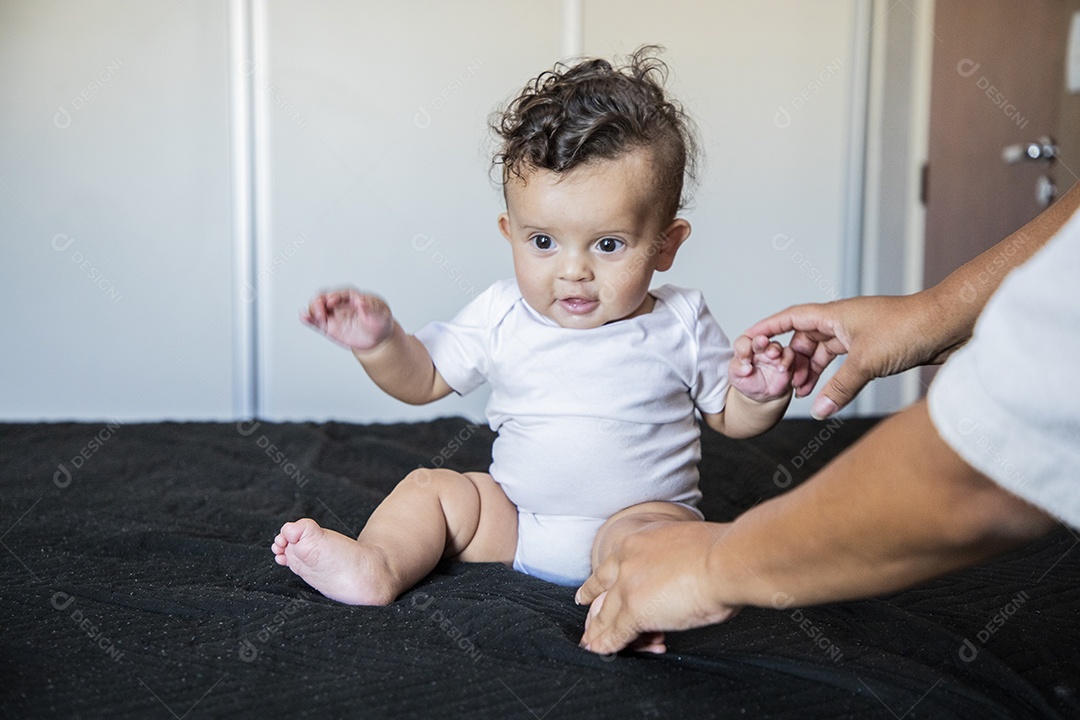 Um bebê lindo sentando na cama brincando