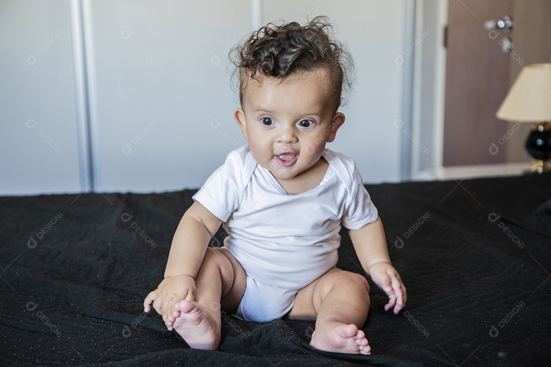 Um bebê lindo sentando na cama brincando