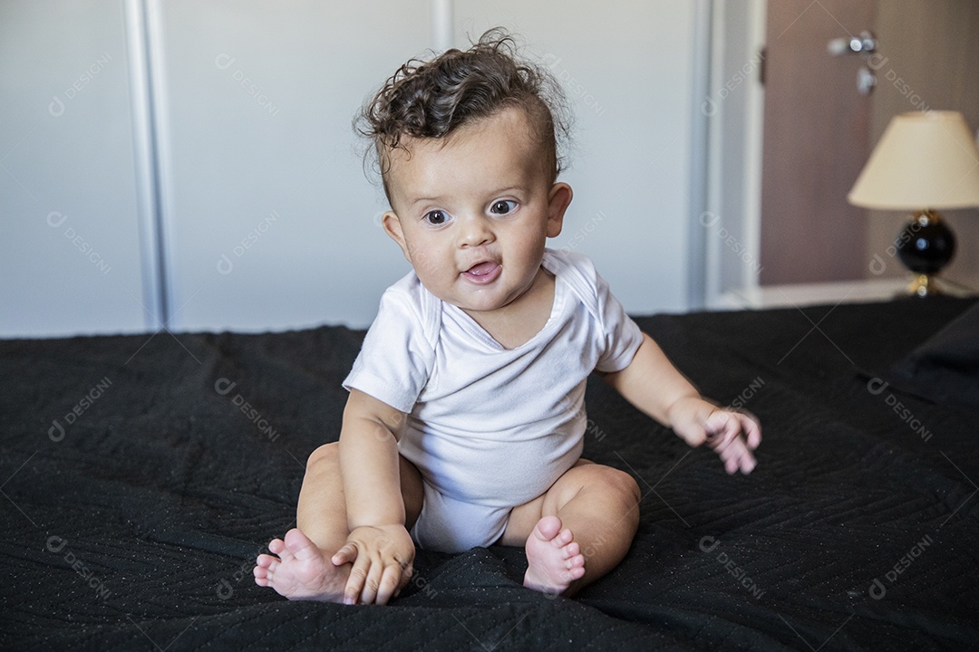 Um bebê lindo sentando na cama brincando