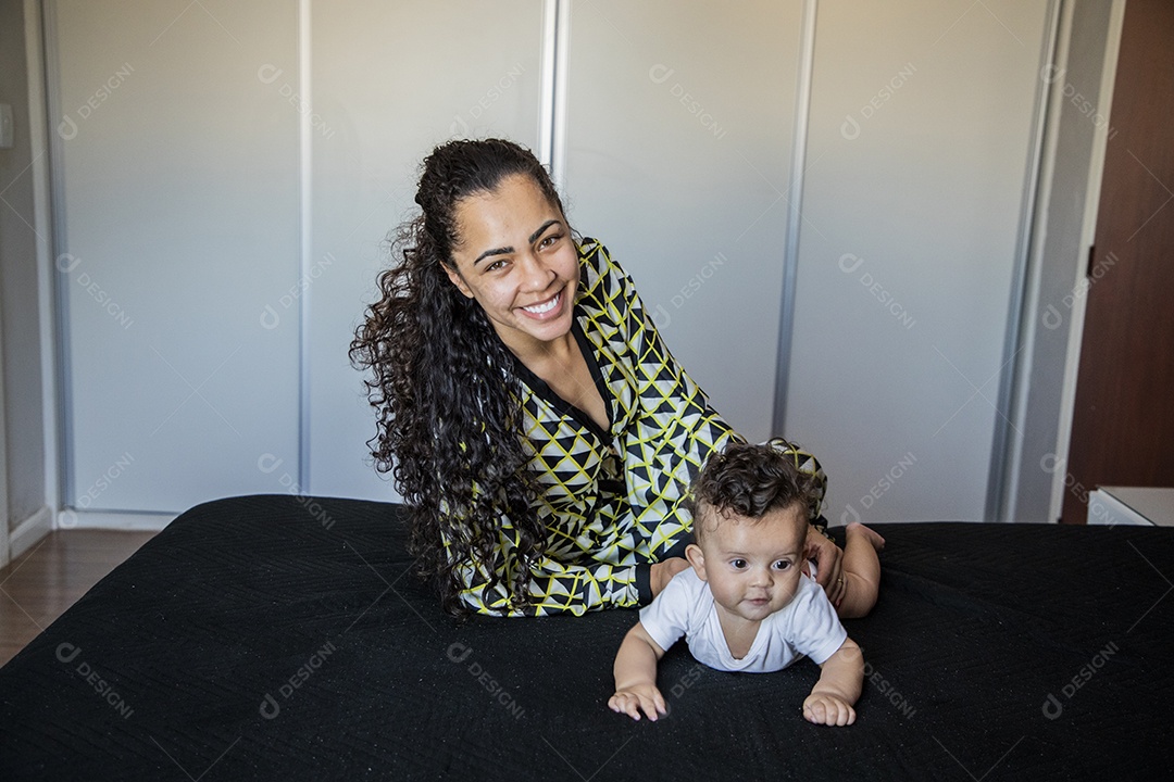 Mãe dedicada e carinhosa com seu bebê feliz na cama