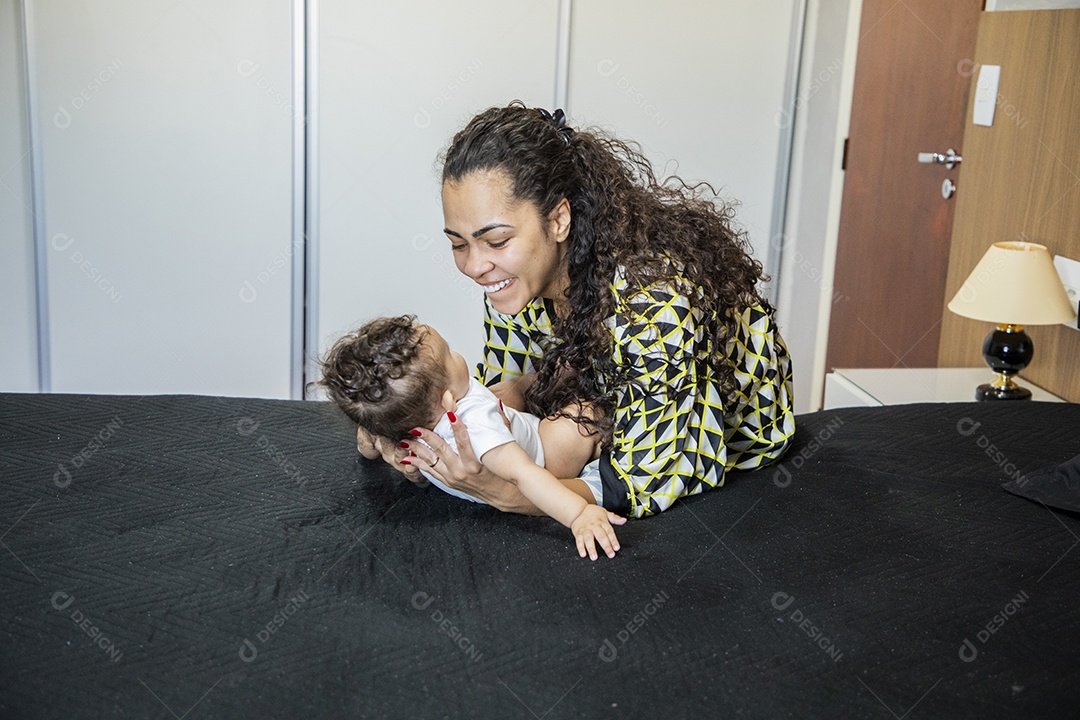 Mãe brincando com seu bebê na cama