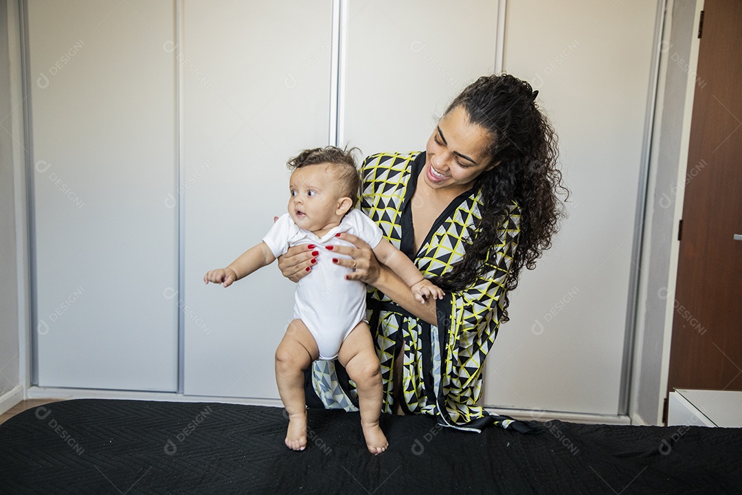 Mãe brincando com seu bebê na cama