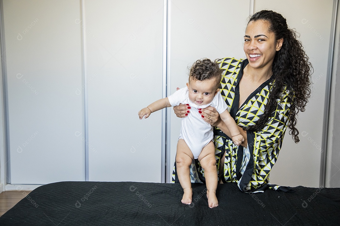 Mãe com seu bebê no colo encima da cama