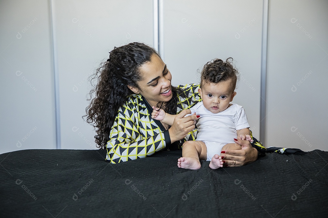 Uma mãe brincando com seu bebê na cama